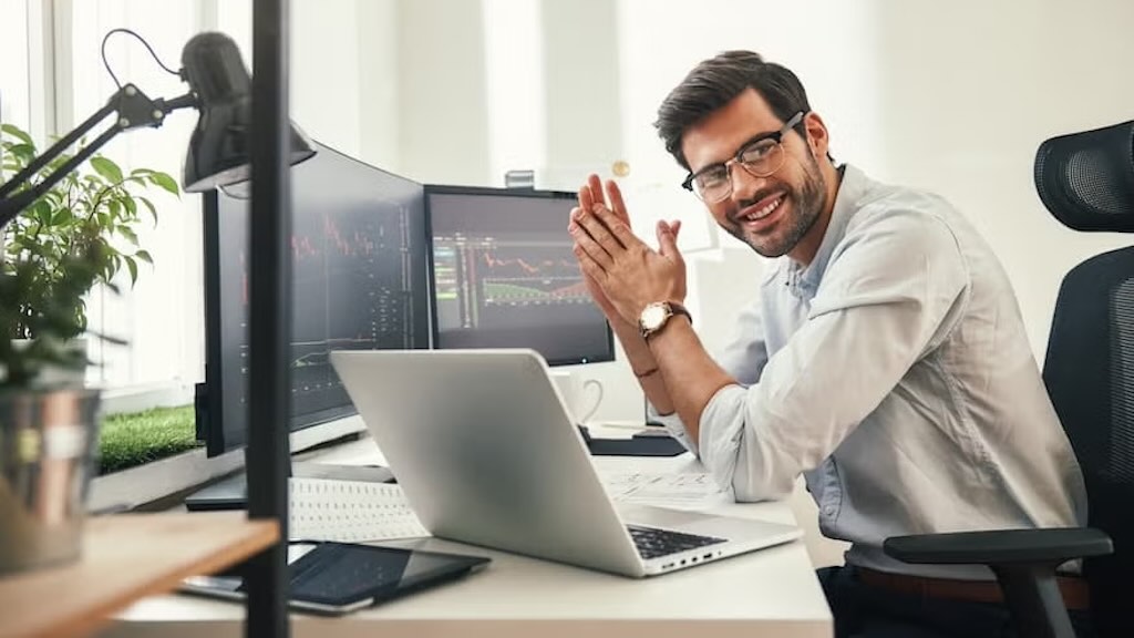 A modern business analyst workspace with multiple screens displaying financial and market data graphs.