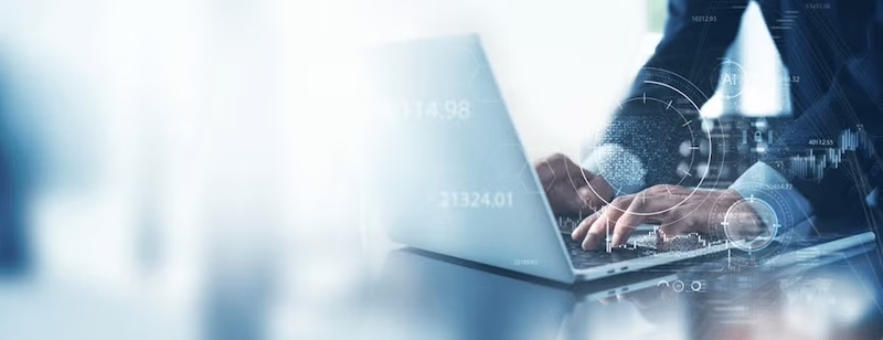 Close-up of hands typing on a laptop with financial data and graphs overlayed.