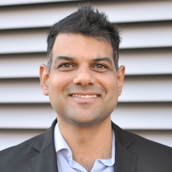 Headshot of Prashant, smiling, with short dark hair, wearing a black blazer and blue shirt.