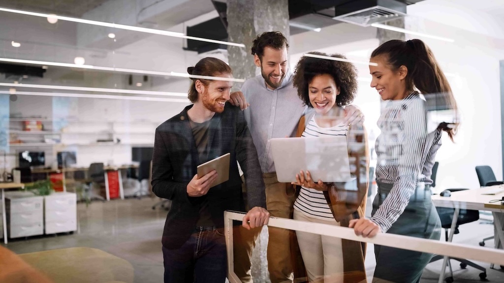 A team of four colleagues working together on a project in a collaborative office setting.