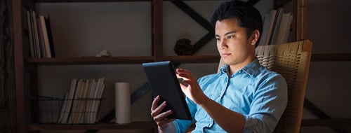 Student sitting on a chair reading tablet
