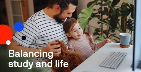 A man holding his daughter while working on a computer, illustrating the challenge of balancing study and life.