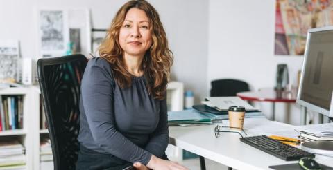 A women’s health professional seated at her desk, working in a clinical setting.