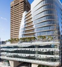 A modern UTS campus building with glass architecture and greenery on a terrace, set against a blue sky.