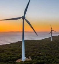 A scenic view of wind turbines at sunset, representing sustainable energy efforts.