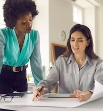 Two women working together on an architecture project, discussing blueprints.