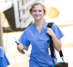 A Master of Advanced Nursing graduate walking outside a hospital carrying a bag and a clip board.