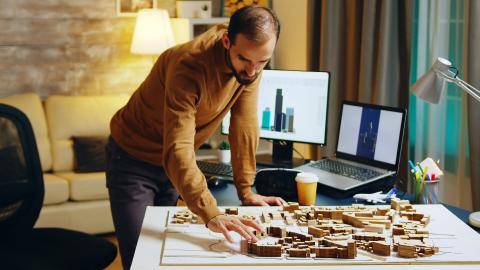 Architect working at night in his home office on a city development project. Drinking coffee.