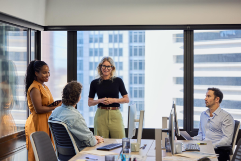 Manager leading a discussion with colleagues during a workplace team meeting.