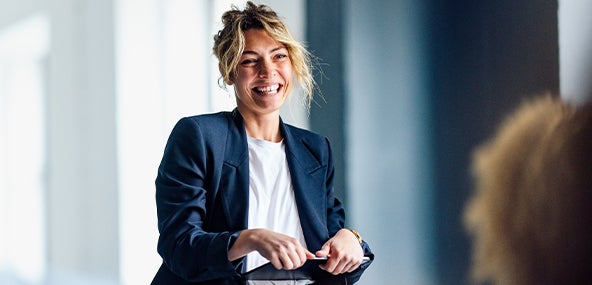 A woman in a business suit smiles confidently, exuding professionalism and positivity.