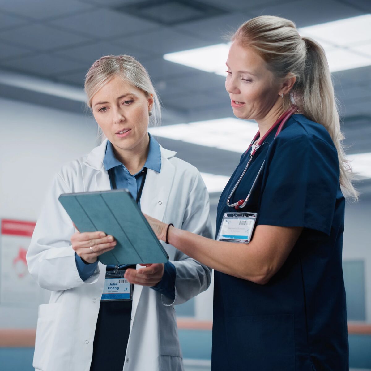 A doctor and a nurse in a busy hospital hallway.
