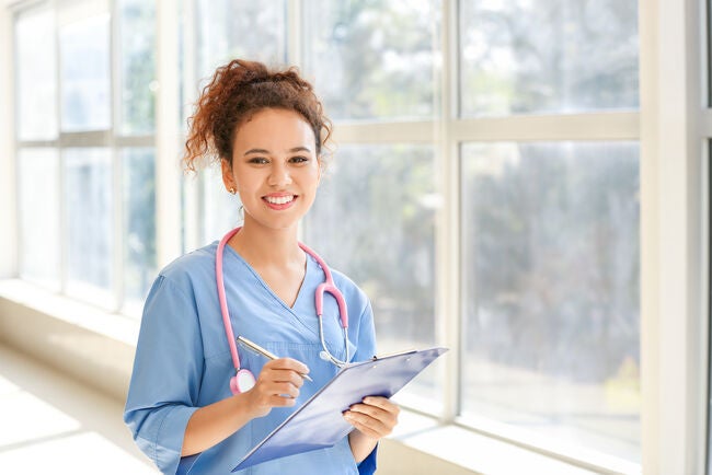 A nurse with a stethoscope near a large glass window.