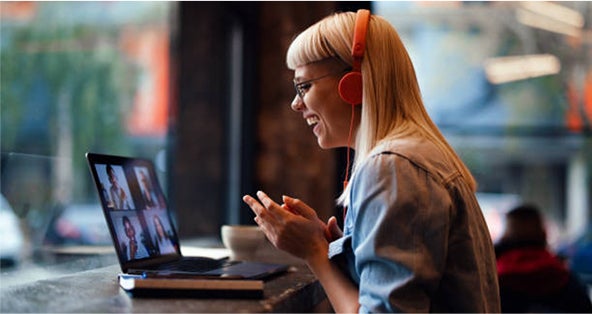 A woman wearing headphones, focused on her laptop screen, engaged in work or a virtual meeting.